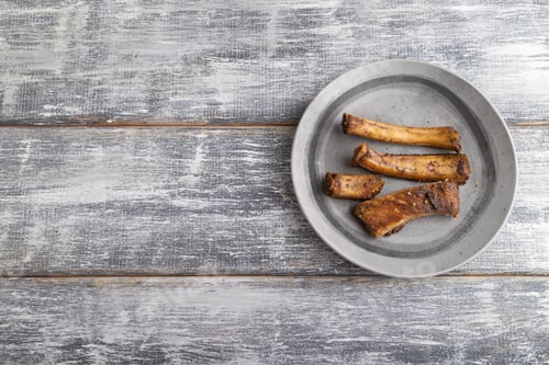 Preview: pork ribs on a wooden plate on a gray. Top view, copy space.