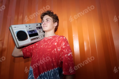 Preview: Carrying Retro Boombox Against Vibrant Orange Wall