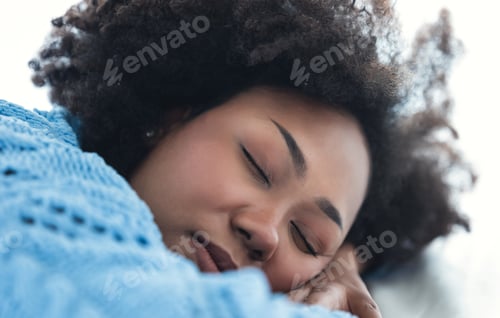 Preview: Beautiful African American woman in warm knitted lying asleep relaxing sleeping in cozy white bed.