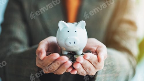Preview: a woman holding piggy bank and coins in hands for saving money and financial concept