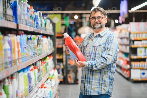 Preview: Portrait of focused man buying household chemicals in supermarket, reading labels on bottles
