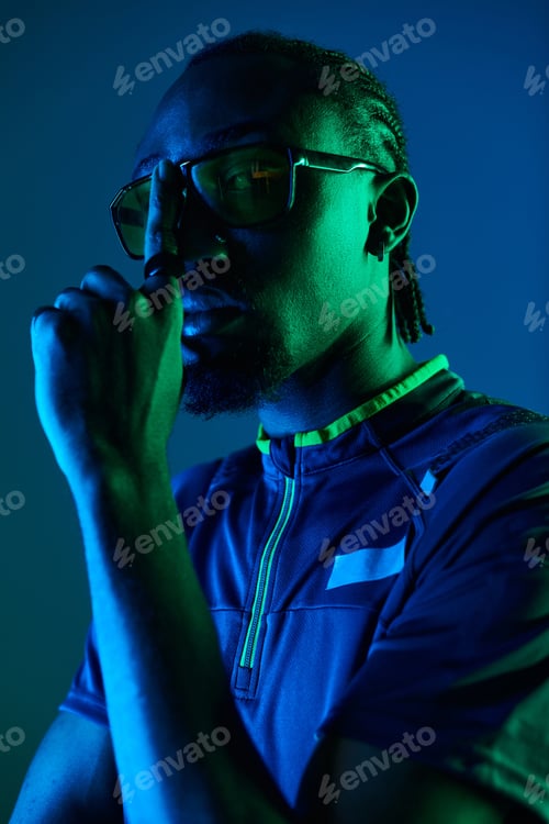 Preview: A stylish young man poses confidently in a neon-lit studio setting at dusk
