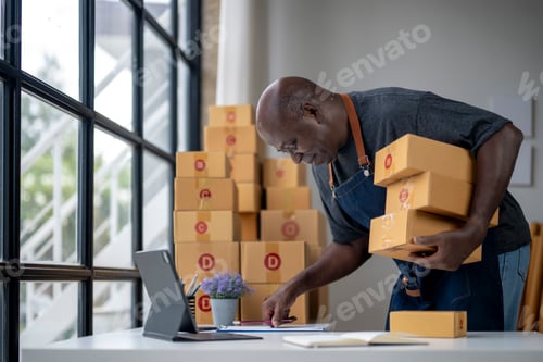 Preview: A man is standing in front of a stack of boxes and looking at a laptop