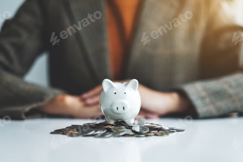 Preview: Closeup image of a woman and piggy bank on pile of coins on the table for saving money concept