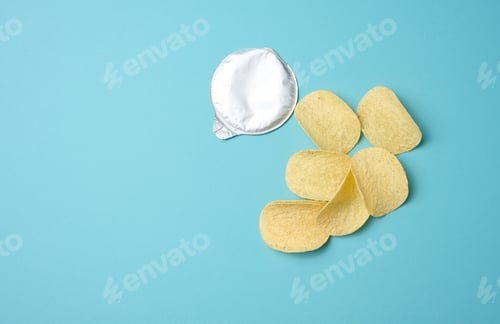 Preview: Round potato chips and foil lid on blue background, top view