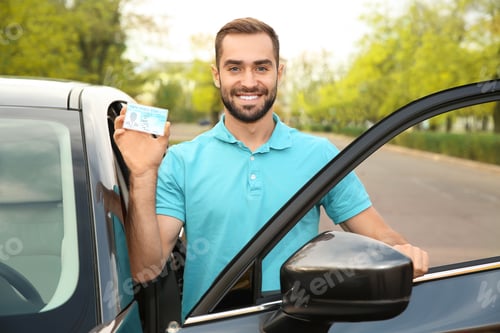 Preview: Young man holding driving license near open car