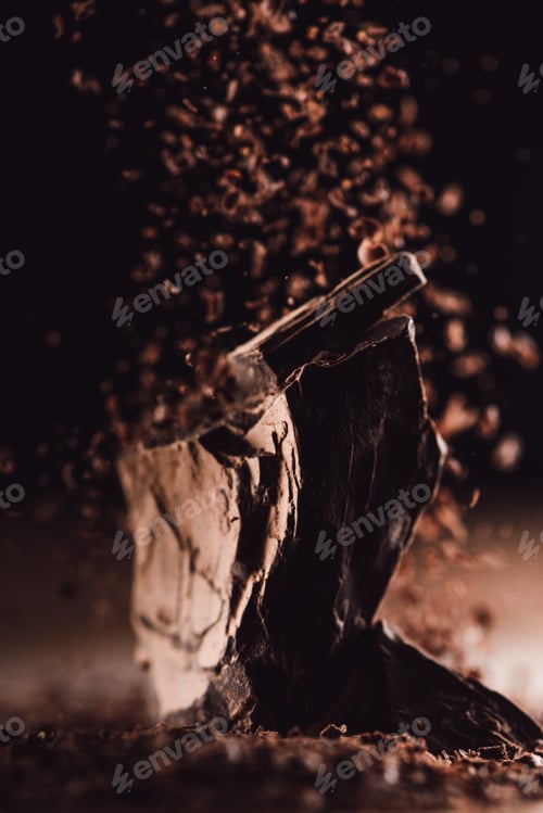 Preview: close up view of grated chocolate falling on pieces of chocolate on black background