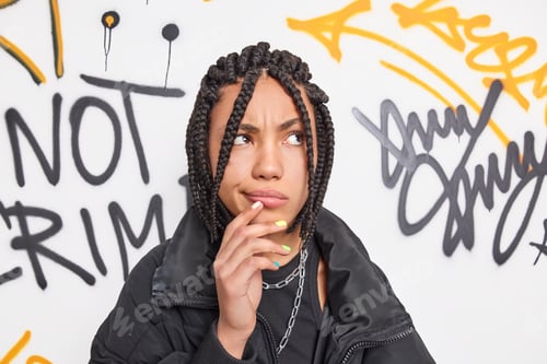 Preview: Street style teenagers concept. Stylish hipster girl has dreadlocks being deep in thoughts keeps han