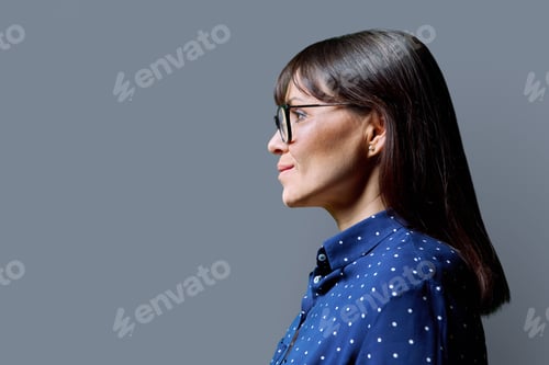 Preview: Profile view of middle aged smiling woman, gray background, copy space