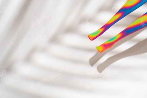 Preview: Neon colored doll legs on white background with palm tree shadow
