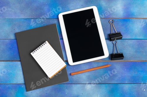Preview: Workplace with blank digital tablet, paper on blue wooden work table. Above view shot