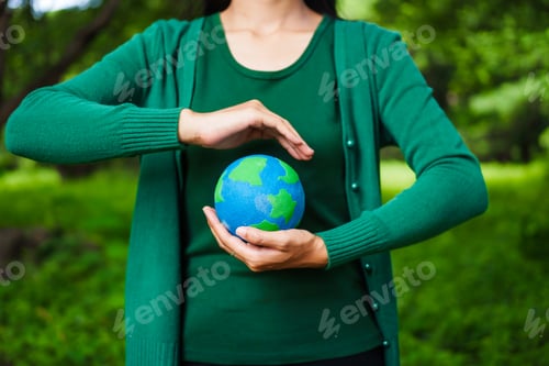 Preview: An Asian woman holds a globe in green forest,symbolizing importance preserving nature.emphasizes