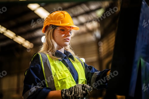Preview: Factory engineer woman standing confident to control panel switch