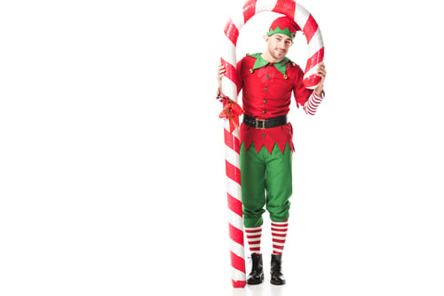 Preview: man in christmas elf costume standing under big candy cane isolated on white