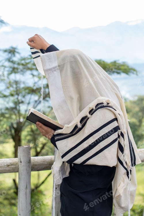 Preview: Jew praying and reading the siddur while raising his right arm to heaven.