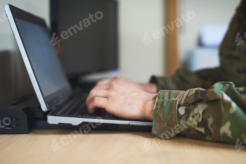 Preview: Cropped shot of a soldier using a laptop in the dorms of a military academy