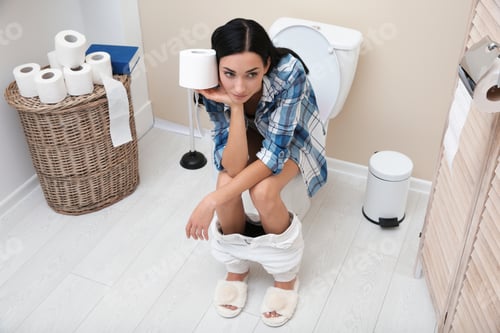 Preview: Woman with paper roll sitting on toilet bowl in bathroom
