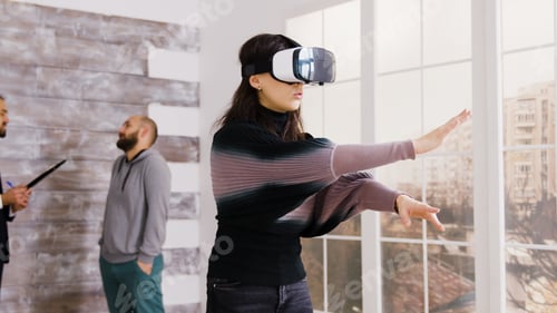 Preview: Female architect using virtual reality goggles in empty apartment