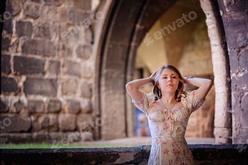 Preview: Woman in Floral Dress Posing by Arched Stone Window