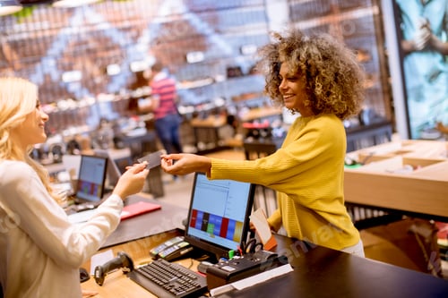 Preview: Happy woman customer paying with credit card in fashion showroom