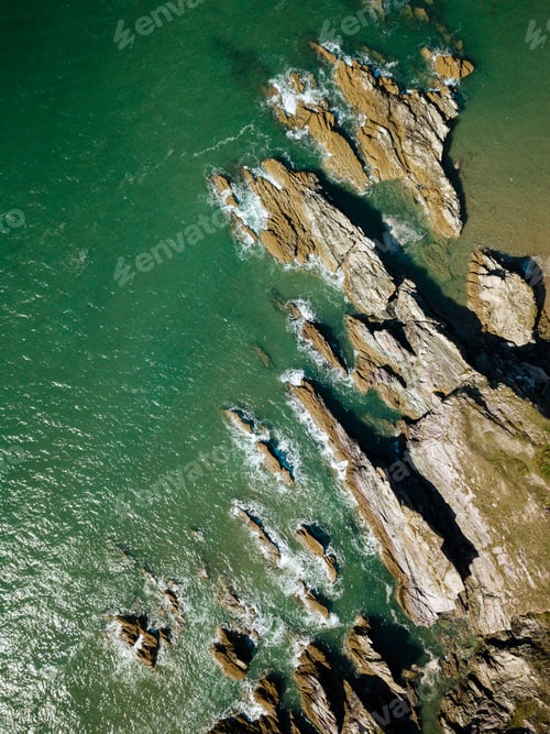 Preview: Aerial view of rugged coastline with waves crashing against the rocks