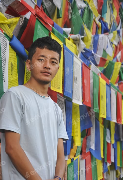 Preview: Photo of a Ladakhi young guy looking at camera, standing against Buddhist prayer flags