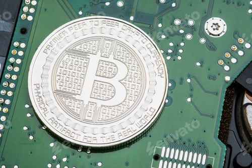 Preview: silver metallic bitcoins on electronic circuit motherboard.crypto currency mining