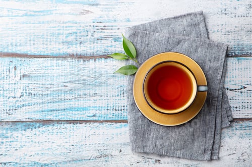 Preview: Cup of tea with green tea leaf. Blue wooden background. Copy space. Top view.