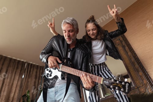 Preview: Father rock guitarist having fun and and dancing with his teenage daughter at home.