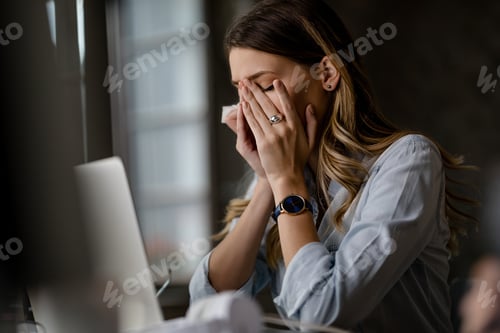 Preview: Young businesswoman having migraine while working late in the office.
