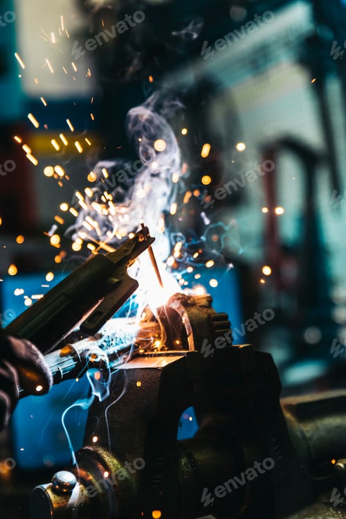 Preview: Mechanic man welding metal material in garage.