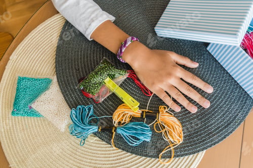 Preview: Hands of a kid with threads bracelets and materials