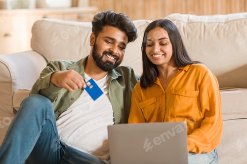 Preview: Indian couple shopping online with laptop and credit card at home
