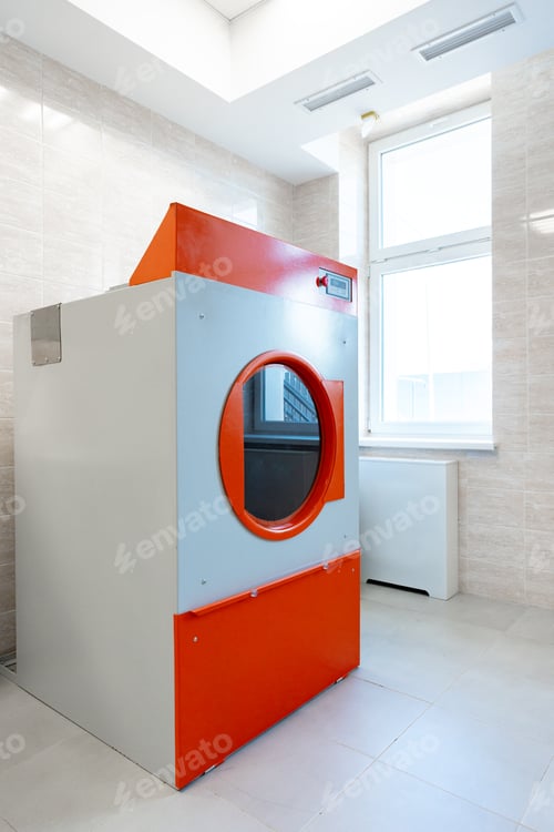 Preview: Modern laundry room featuring a large industrial washer with orange and gray design in a well-lit
