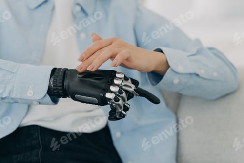 Preview: Girl is setting up her bionic hand and pressing buttons. Young woman with artificial arm at home.