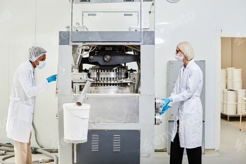 Preview: Two Production Workers Inspecting Tablet Press Machine at Pharmaceutical Factory