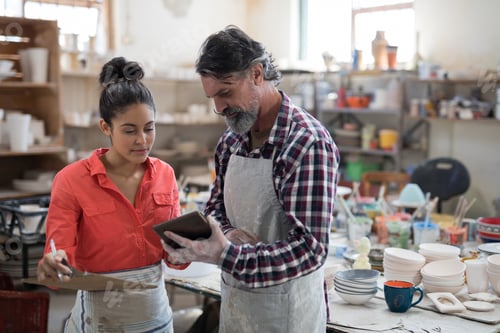 Preview: Male and female potter discussing over tablet pc
