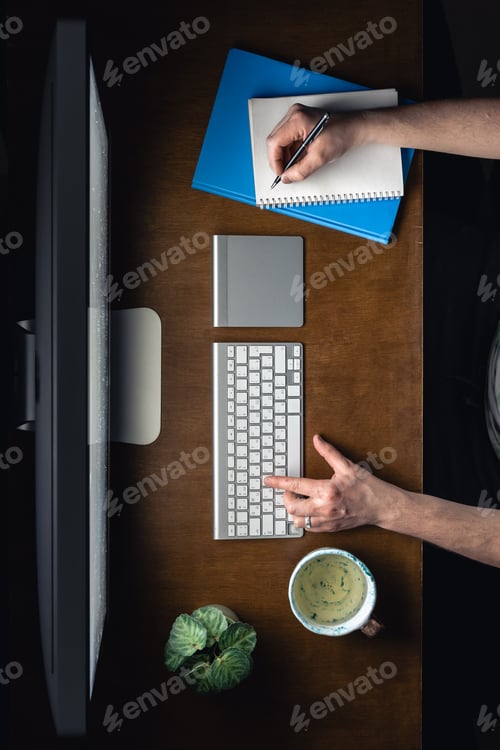 Preview: Top view, a man working at a computer with a notepad and a cup of tea at night.