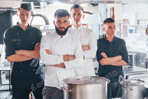 Preview: Group of people in white uniform standing together at kitchen. Cooking food