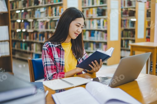 Preview: Female college student working on laptop and searching for books to study