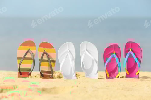 Preview: Different bright flip flops in sand. Beach accessories