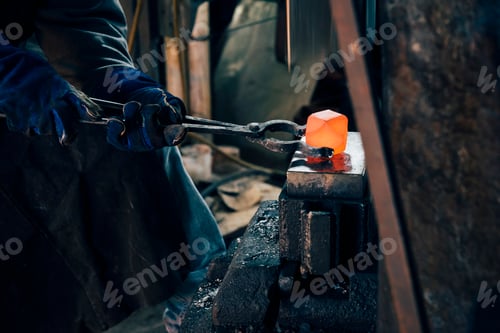 Preview: Gloved hands of blacksmith using tongs for red hot metal