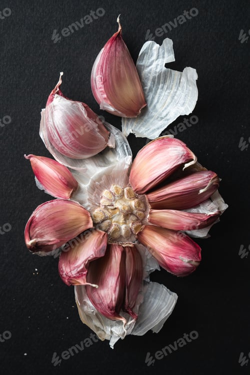 Preview: Vertical top view of a peeled red garlic on a black surface