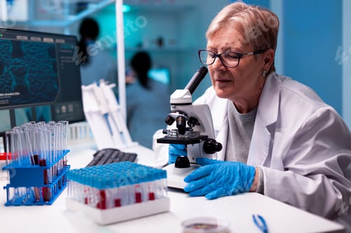 Preview: Professional senior scientist using microscope in health study