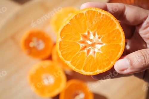 Preview: Freshly cut orange revealing juicy segments in hand