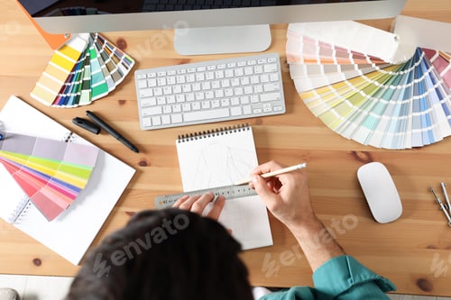 Preview: Man drawing in sketchbook with pencil and ruler at wooden table, top view