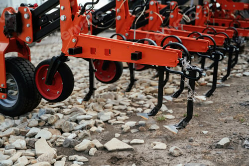 Preview: Close-up view of orange agricultural machine on rocky ground