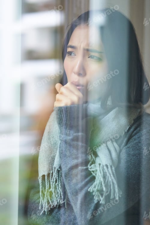 Preview: Portrait of sad ill korean woman looking out of the window, staying at home due to coronavirus