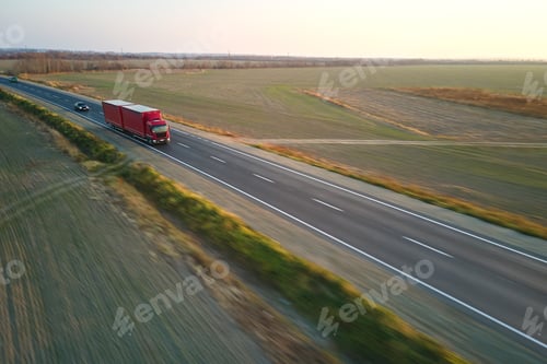 Preview: Aerial view of blurred fast moving semi-truck with cargo trailer driving on highway