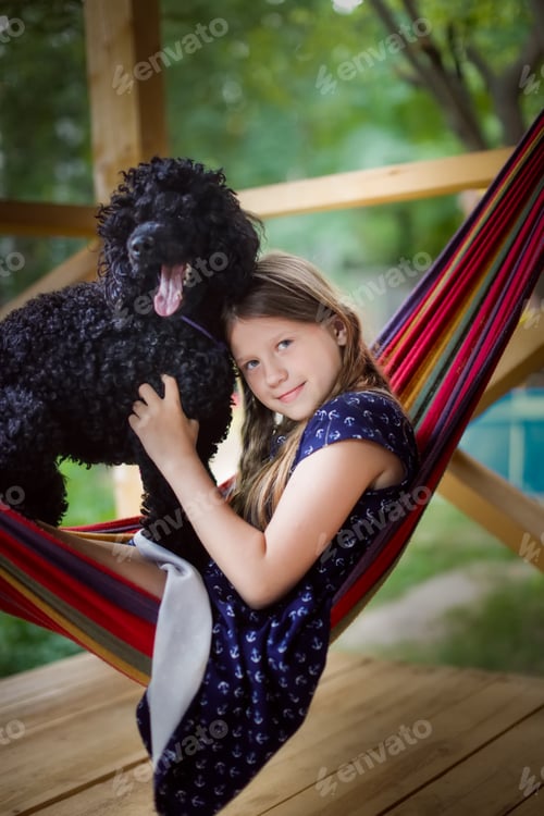Preview: kid girl and black poodle resting on hammock, children and pets,